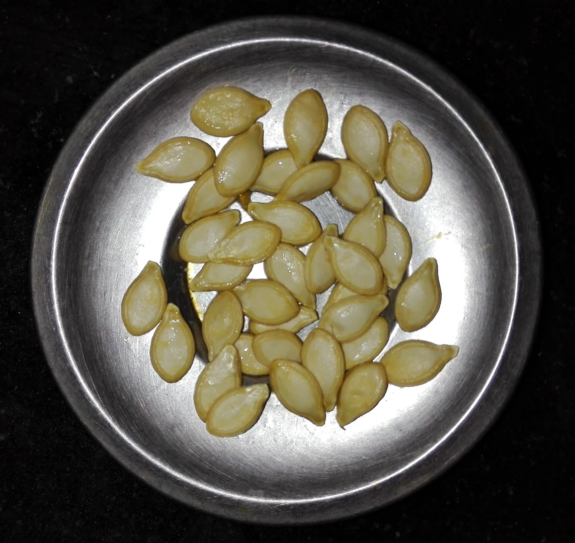 छोटी धातु की कटोरी में कद्दू के बीज